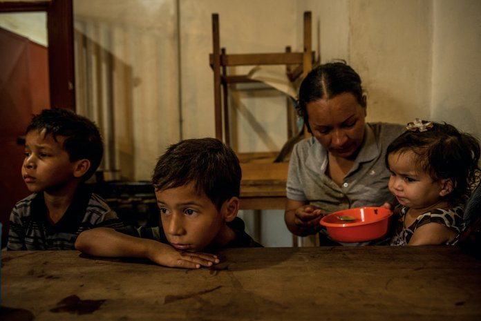 Oriana Caraballo, feeds her children Brayner, 8, Rayman, 6, and Sofia, 22 months, at a soup kitchen in Los Teques, Venezuela.